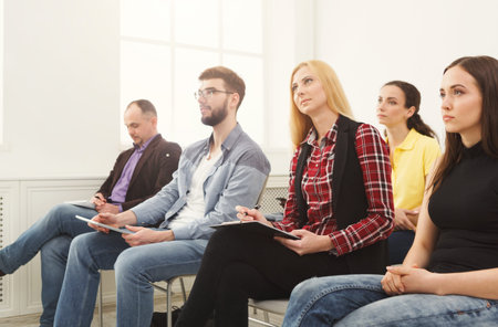 Group of People Listening and Taking Notes at a Workshop in a Bright Room