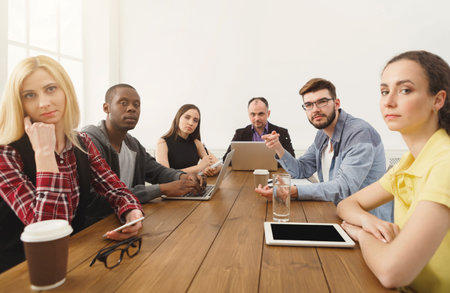 Group of People in a Meeting Room Engaged in Discussion and Work at a Table