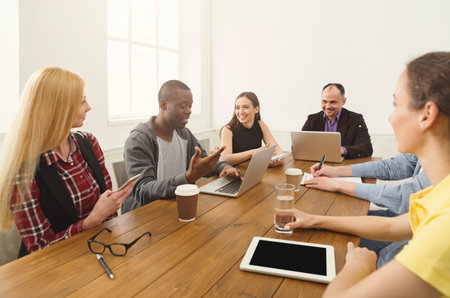 Group Discusses Ideas During a Meeting in a Bright Room With Laptops and Coffee