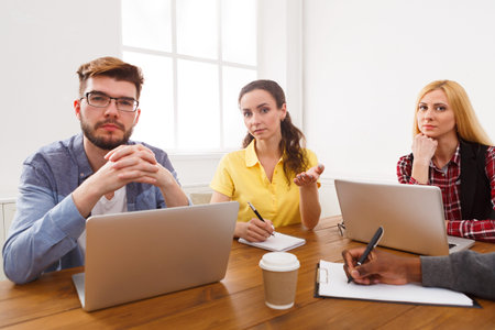 Group of People Engaged in a Discussion With Laptops in a Bright Room During the Day