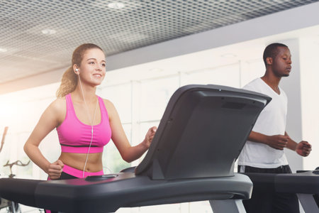 Group of People Exercising on Treadmills in Fitness Center During Evening Hours