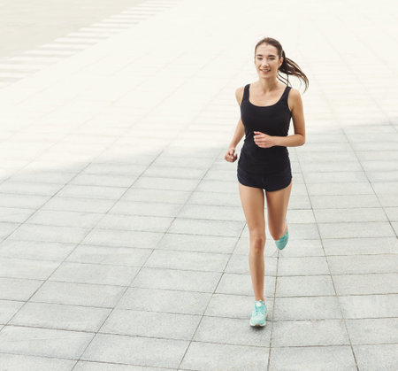 Woman Runs on a Smooth Pavement During Daytime for Exercise and Fitness in an Urban Area