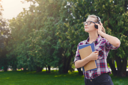 Young Woman Listens to Music While Enjoying a Sunny Day in the Park