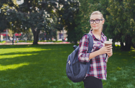 A Young Adult Stands in a Park With Green Grass