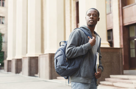 Young Man Walking Outside a Building With a Backpack and School Materials in the Cityの写真素材