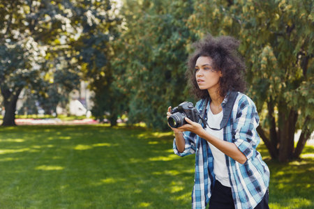 Young Woman Takes Photos in a Green Park During Daytime Using a Digital Cameraの写真素材
