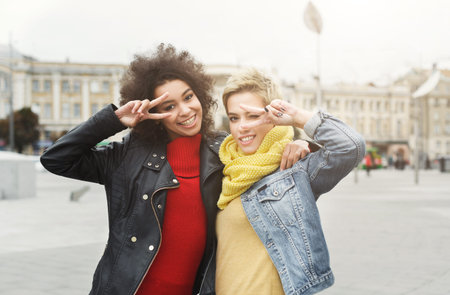 Set of Friends Posing in a City Square With Smiles and Hand Signs in the Daytimeの写真素材