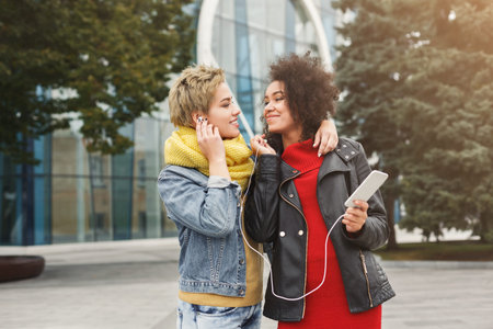Friends Enjoying Music Together Outside During a Sunny Day in the Cityの写真素材