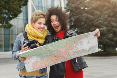 Two Friends Explore a New City While Looking at a Map During Daytime