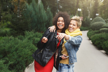 Women Laugh and Interact While Walking in a Park During Daytime in an Outdoor Setting With Greeneryの写真素材