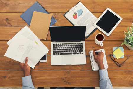 Workspace Collection With Documents, Laptop, Tablet, and Coffee Cup Arranged on Wooden Table