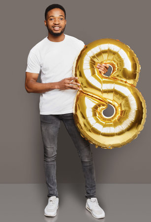 Man Holds Large Golden Number Balloon in a Simple Setting for a Celebration or Event