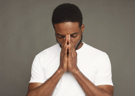 Man in White Shirt Holds Hands Together in Front of His Face During a Moment of Reflection