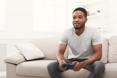 Man Plays Video Games on Couch in Living Room During Leisure Time at Home