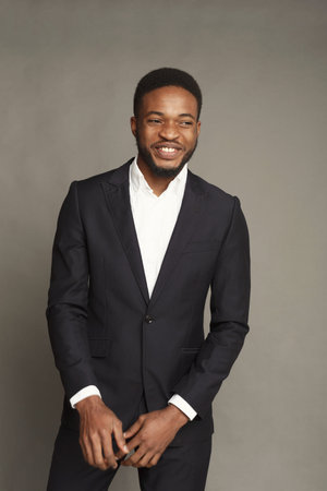 Man in Suit Stands Confidently While Smiling for the Camera in a Plain Background Setting