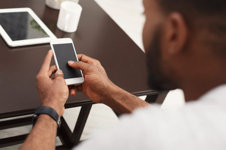 Person Using Mobile Phone at a Table With a Tablet and Mug Nearby During Day Time