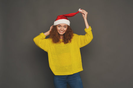Woman With Curly Hair Wears Festive Hat and Smiles in Indoor Settingの写真素材