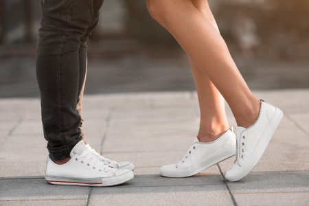 Couple Standing Close Together Wearing White Shoes on a City Street During Daytime Hours