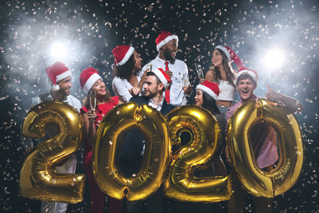 Friends holding 2020 golden balloons at New Year party
