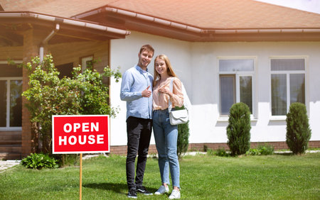 Happy home owners with house key in front of their new property, empty space
