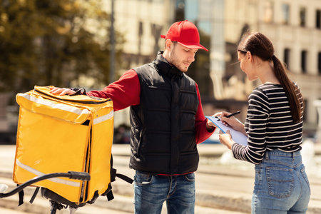 Customer Girl Signing Papers Standing With Delivery Guy Outdoors