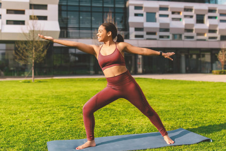 Happy Young Latina Woman Practicing Yoga Pose Outdoors On Mat In Park, Weight Loss Concept