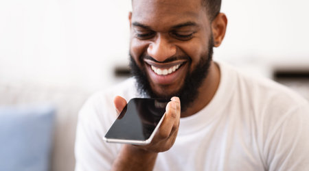 African Guy With Phone Using Voice Assistant App Indoors, Closeup