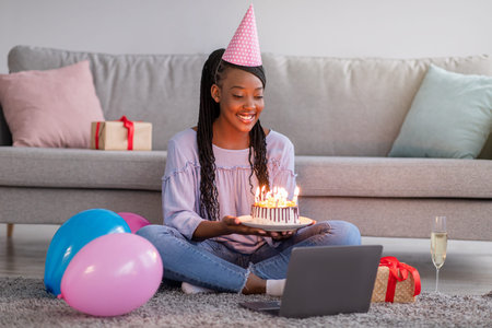 Happy black lady in party hat celebrating birthday online