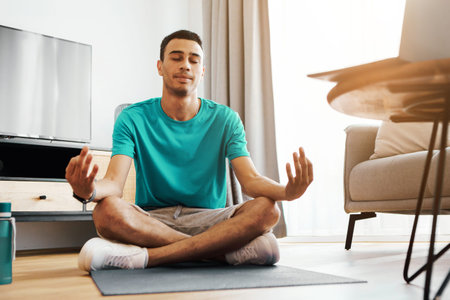 Meditating Young Man In Living Room, Focused And Calm Mindfulness Concept