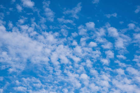 Blue sky with light fluffy white clouds background.の写真素材