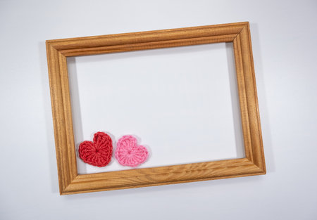 Wooden frame on a white background with knitted decorative hearts design template mockup and an empty space for text.の写真素材