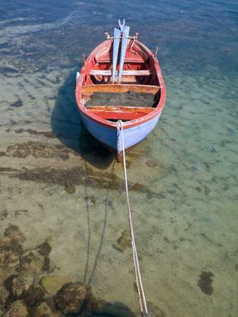 Coloured rowboat in clear sea.の写真素材