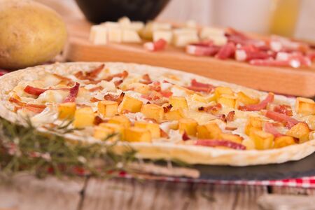 Tart with fried potato, raclette cheese and smoke flavour bacon.の写真素材