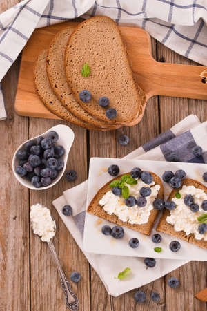 Rye bread with cottage cheese, blueberries and honey.の写真素材