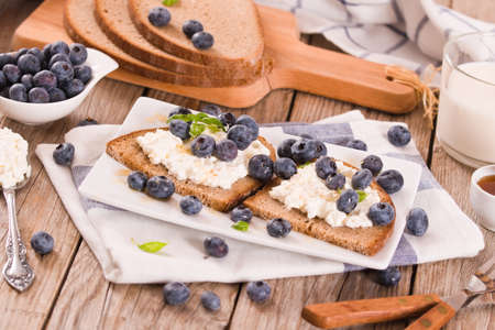Rye bread with cottage cheese, blueberries and honey.の写真素材