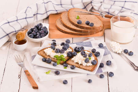 Rye bread with cottage cheese, blueberries and honey.の写真素材