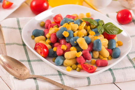 Colored gnocchi with vegetables and sweet corn.の写真素材