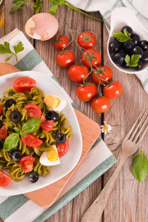 Fusilli pasta with cherry tomatoes, eggs and black olives.の写真素材