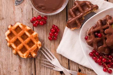 Waffles with chocolate topping, red currant and hazelnuts.の写真素材