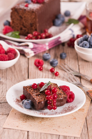 Chocolate sponge cake with fresh fruit on white dish.の写真素材