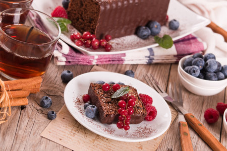 Chocolate sponge cake with fresh fruit on white dish.の写真素材