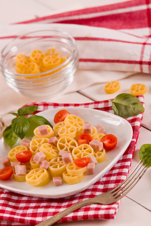 Pasta wheels with tomato and ham.の写真素材