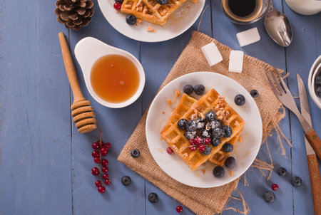 Waffles with red currant and blueberries on white dish.の写真素材