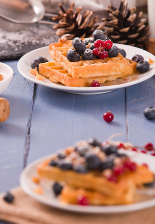 Waffles with red currant and blueberries on white dish.の写真素材