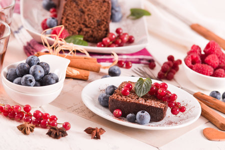 Chocolate sponge cake with fresh fruit on white dish.の写真素材