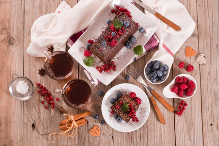 Chocolate sponge cake with fresh fruit on white dish.の写真素材