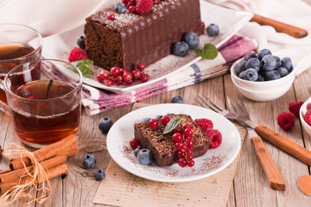 Chocolate sponge cake with fresh fruit on white dish.の写真素材