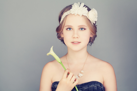 Child Girl with Blonde Hair. Bohemian Boho Chic Hairstyle and Lily Flowerの写真素材