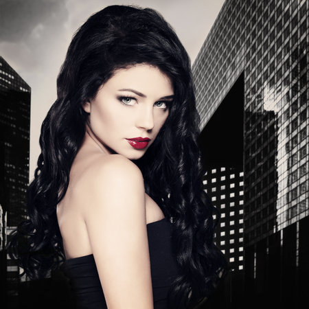 Fashion Brunette Woman with Long Black Curly Hairstyle on City Backgroundの写真素材