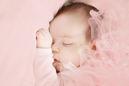Little girl sleeping on light pink backgroundの写真素材